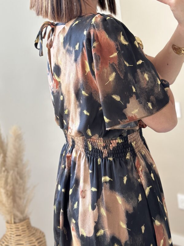 La robe légère et fluide, parfaite. Ses petites manches fluides couvrent les hauts de bras, légèrement ouvert au dos . Doublée , avec des petites touches de dorés, marron et noir
